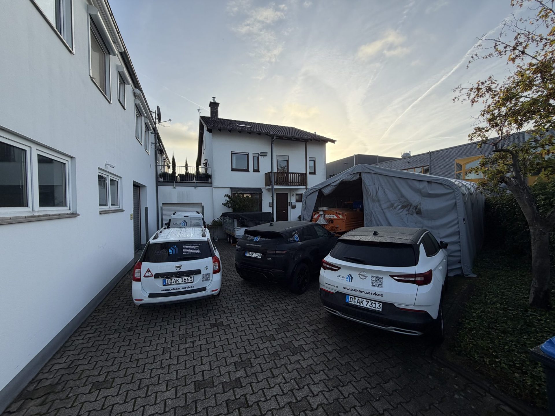 Servicefahrzeuge mit AKOM-Beschriftung auf dem Hof des Firmensitzes